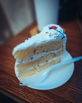 A slice of layered vanilla cake with creamy frosting and a drizzle of caramel sauce.