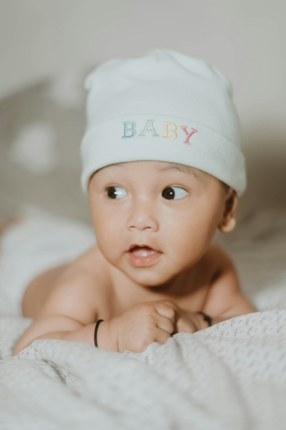 a baby wearing a white hat on top of a bed