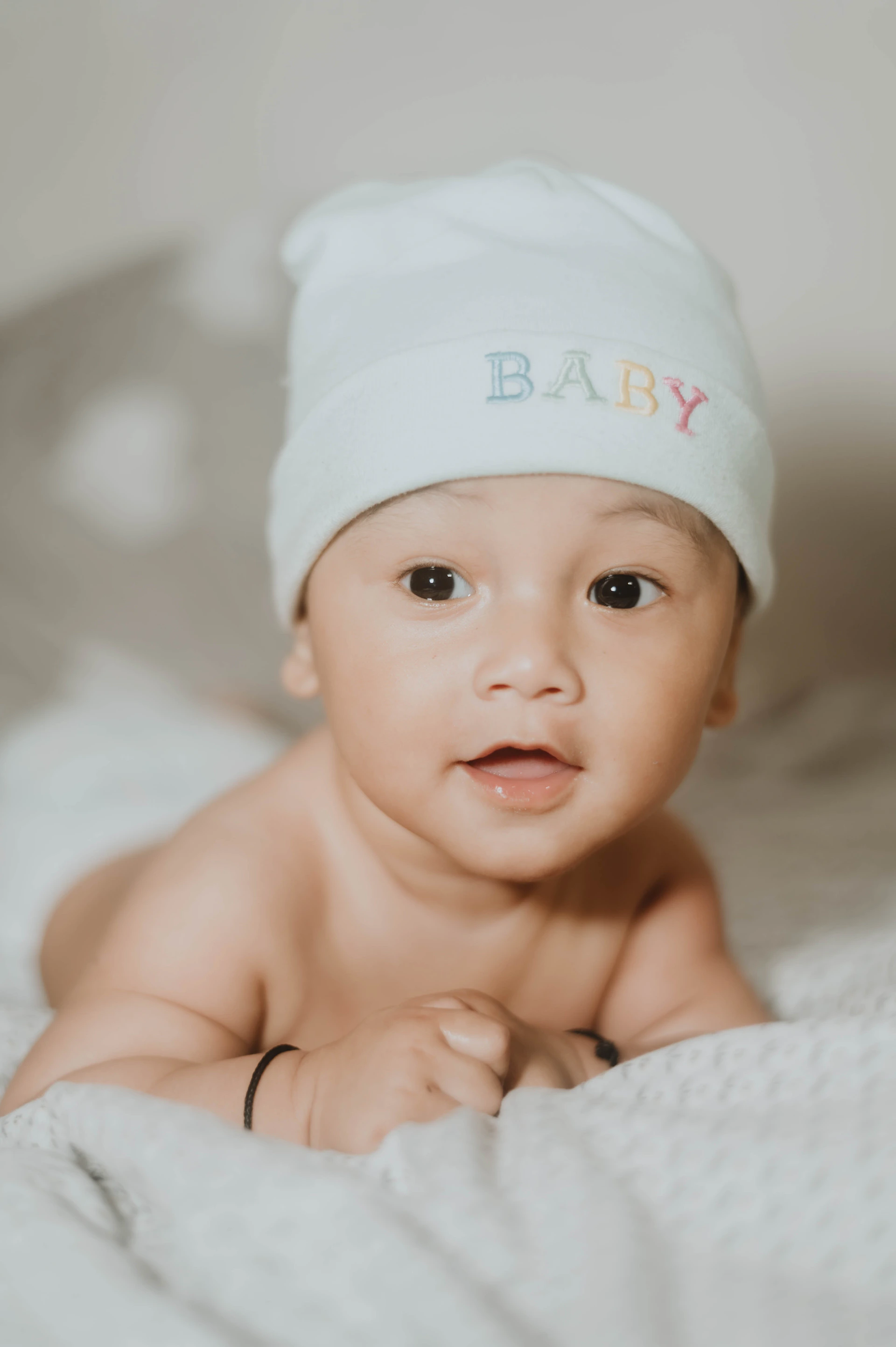 a baby laying on a bed wearing a white hat