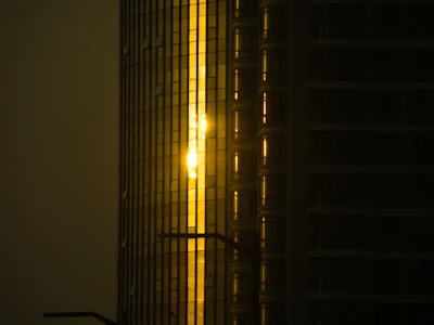 Ultra-realistic image of a modern luxury residential tower at sunset with golden light reflecting on glass surfaces.