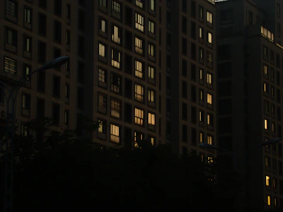 Evening view of a city block featuring erdvėja’s affordable housing with warm lighting.