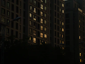 Evening view of a city block featuring erdvėja’s affordable housing with warm lighting.