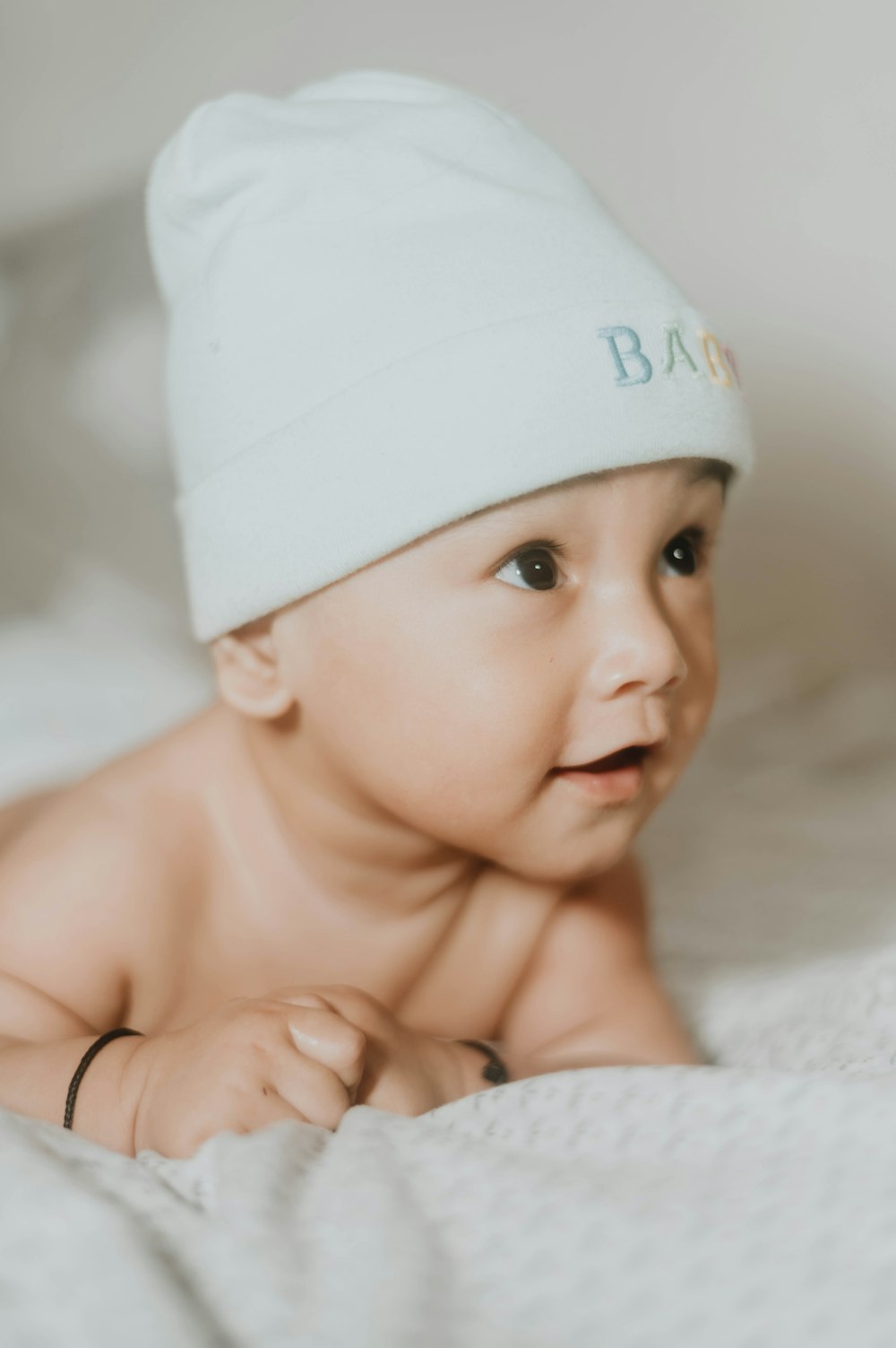 a baby laying on a bed wearing a white hat