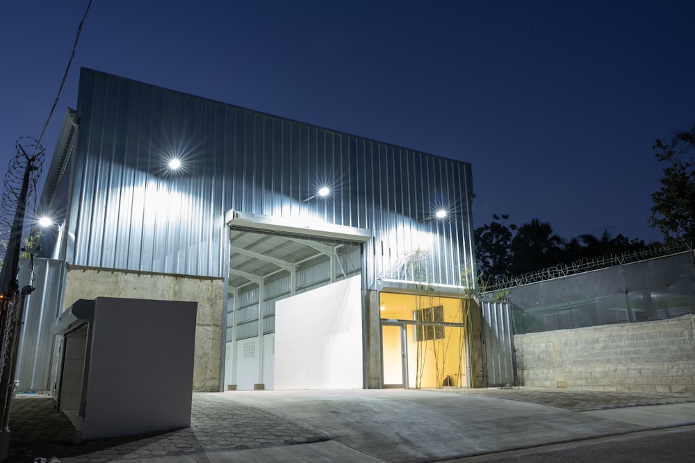 a large metal building with lights on at night