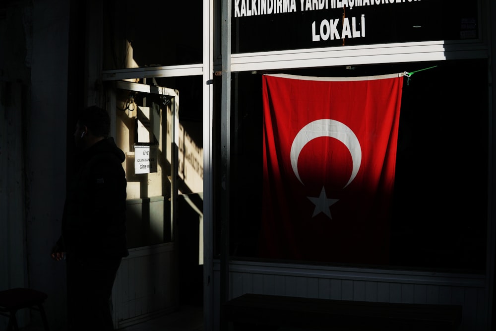 a person standing in front of a building with a flag