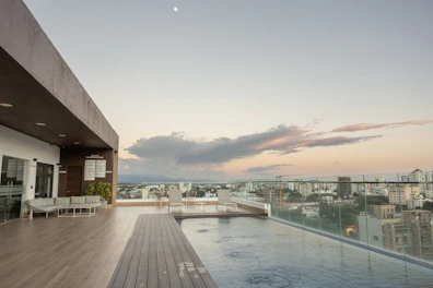 Rooftop infinity pool at Beacon Executive Suite with loungers and panoramic views of George Town at sunset.