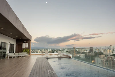 Luxurious hotel rooftop pool overlooking a vibrant city skyline at sunset.