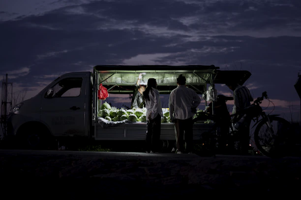 Close-up of a driver checking cargo inside a trailer filled with fresh produce under soft lighting.