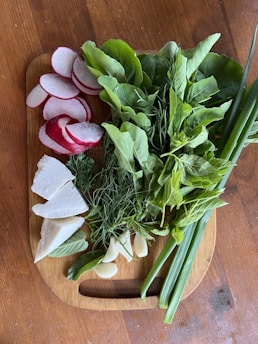 A rustic wooden board displaying an assortment of pickled vegetables alongside fresh herbs.