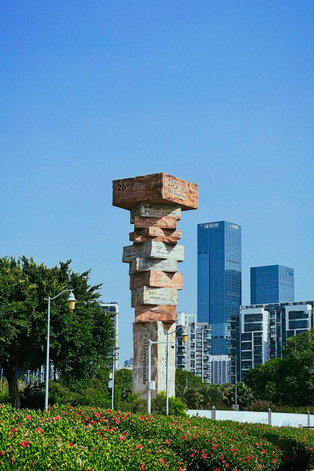 a stone sculpture in a park with a city in the background