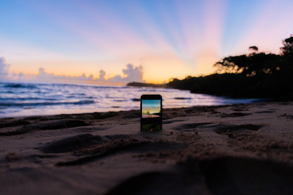 a cell phone sitting on top of a sandy beach