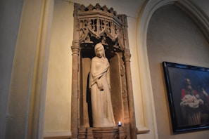 A softly lit candle burning beside a small statue of Saint Jude in a quiet home altar.