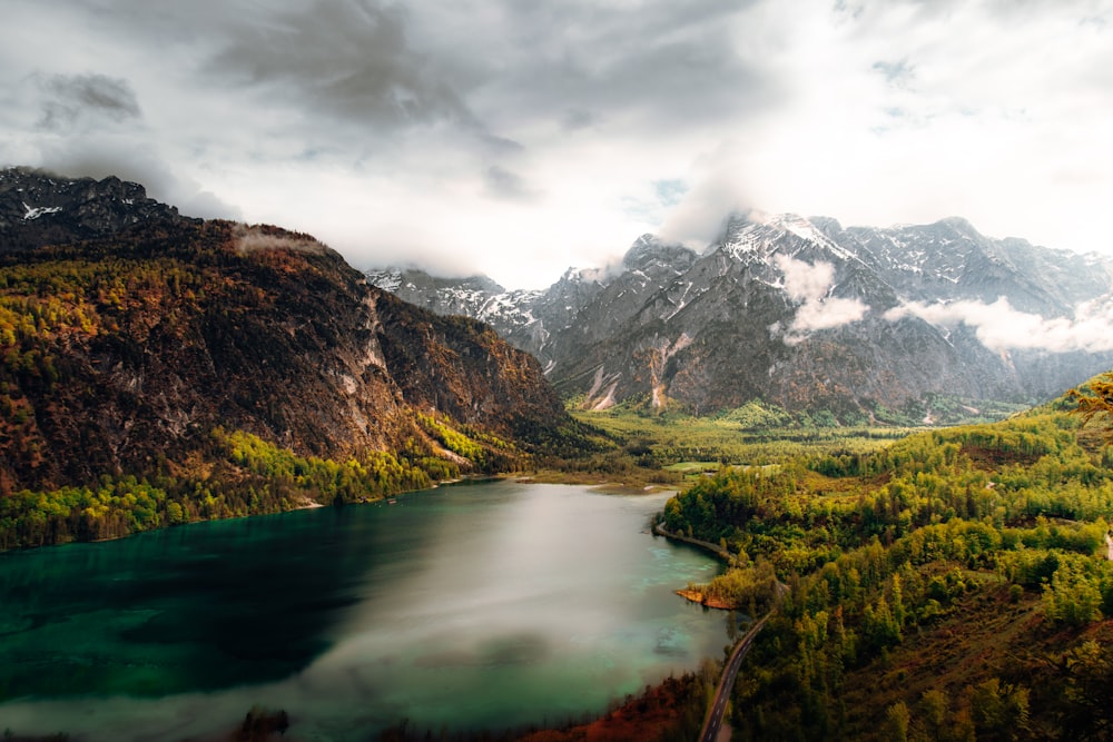 a lake surrounded by mountains under a cloudy sky