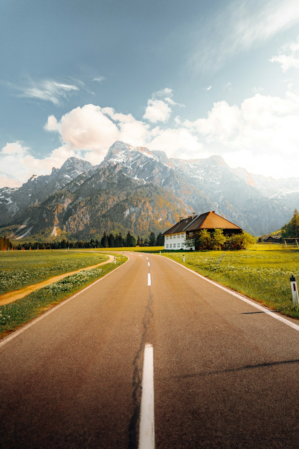 an empty road with a house in the distance