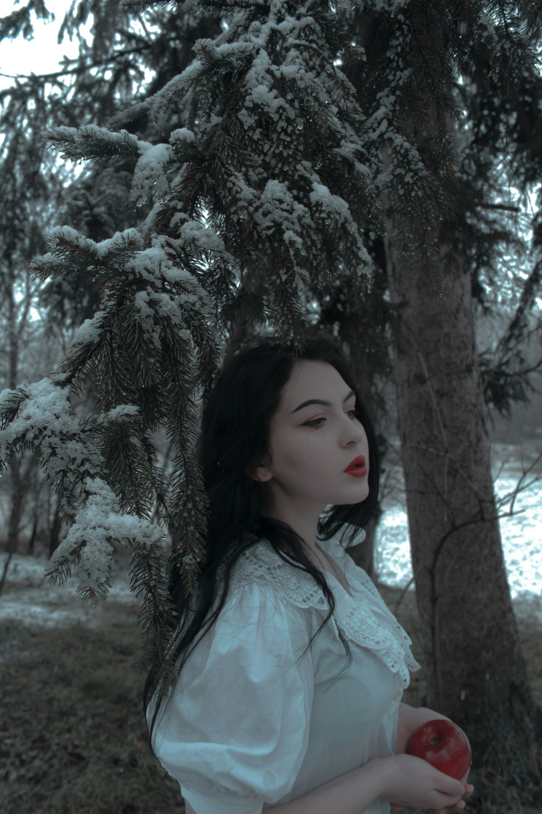 a woman in a white dress holding a red apple