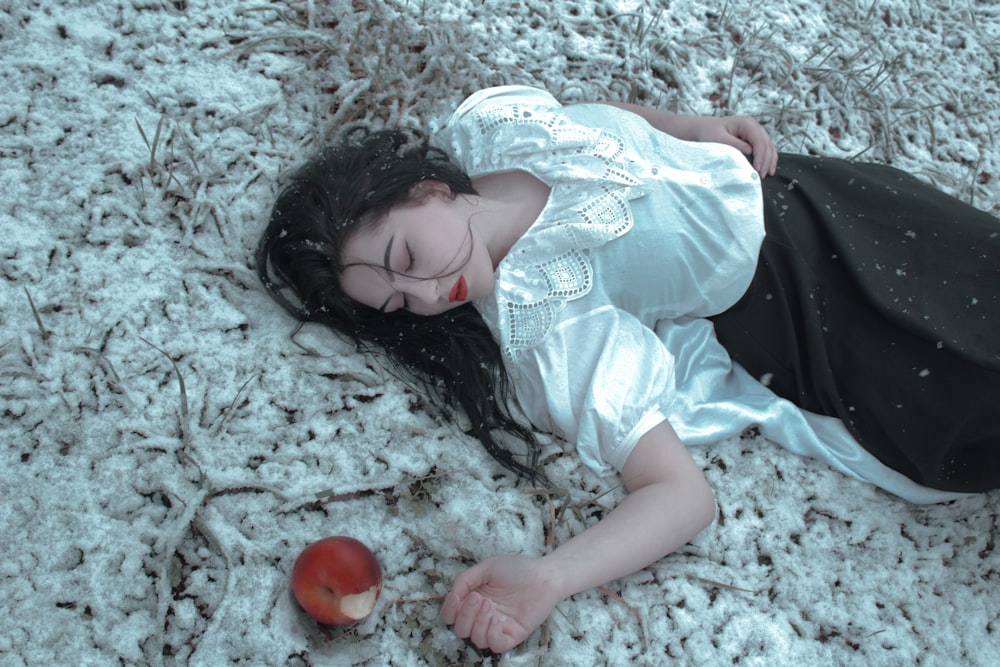 a woman laying on the ground next to an apple
