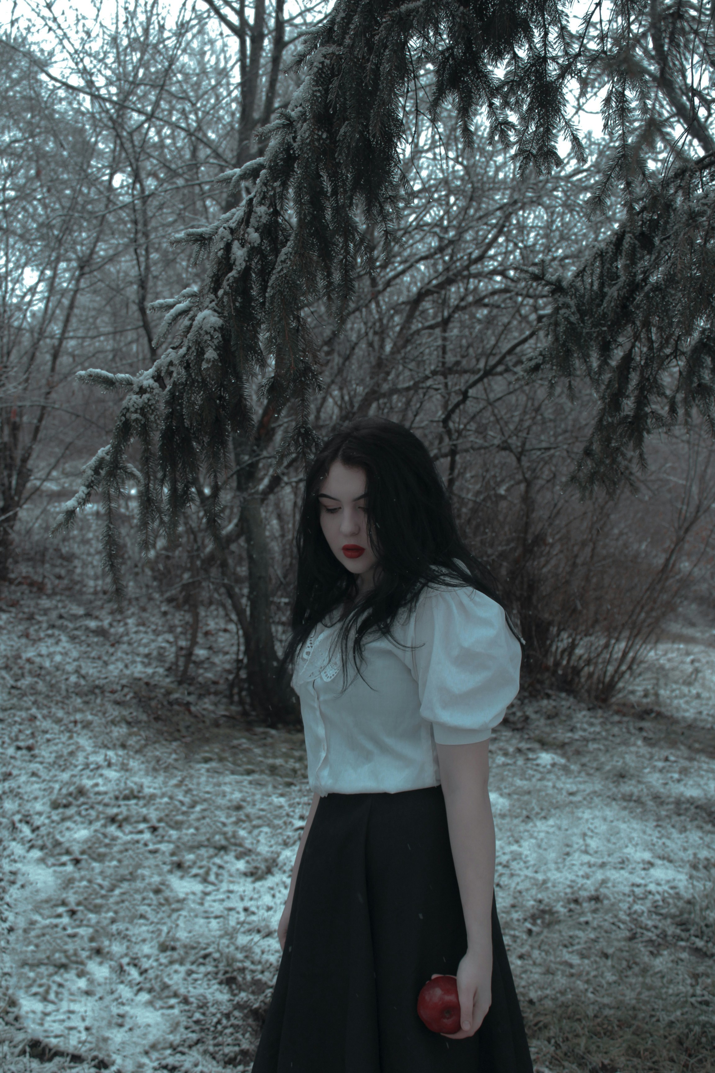 a woman in a white shirt and black skirt holding an apple