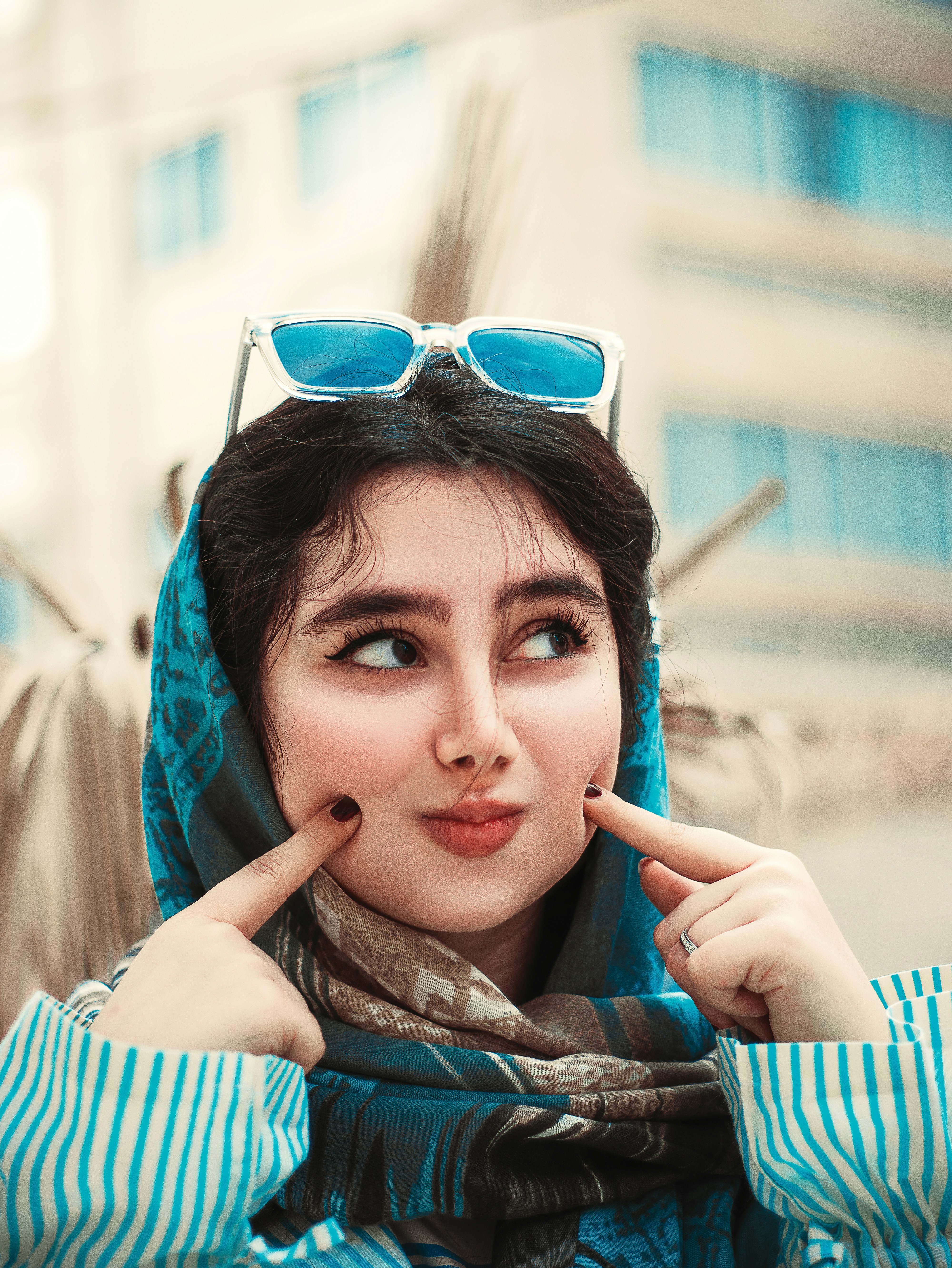 a woman in a scarf and sunglasses poses for a picture