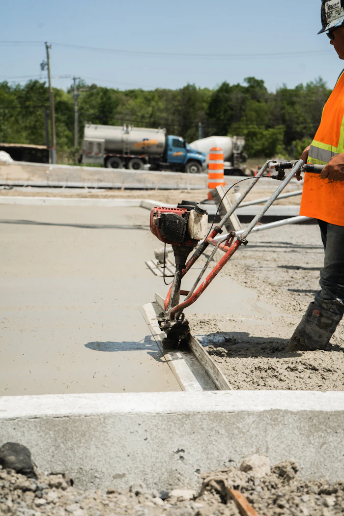 Worker power-screeding and finishing a freshly poured slab edge