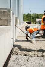 two men in orange vests working on a building