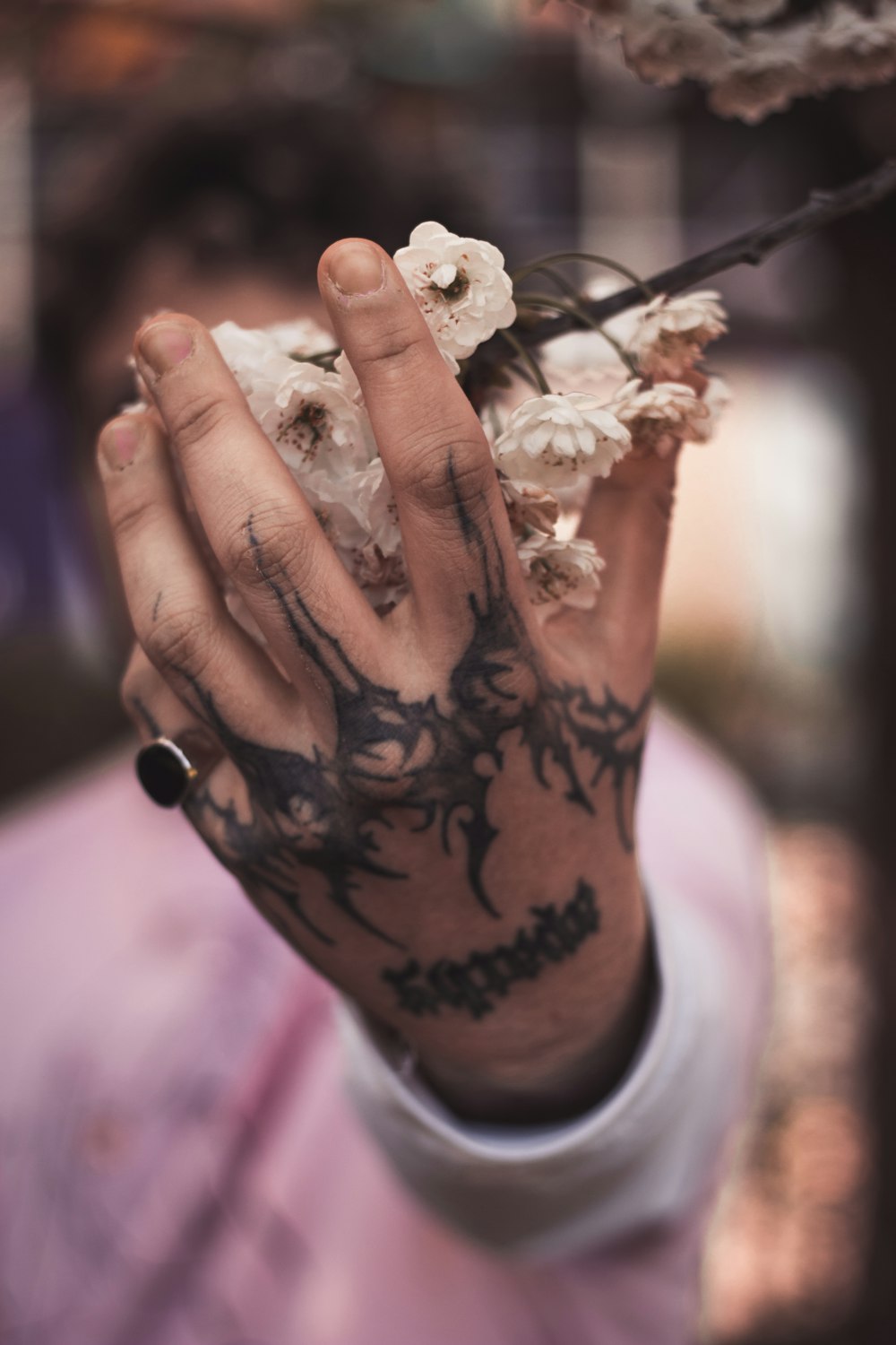 eine Person mit Tätowierungen, die eine Blume in der Hand hält
