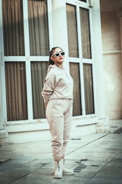 a woman wearing beige co-ord & sunglasses standing on a sidewalk