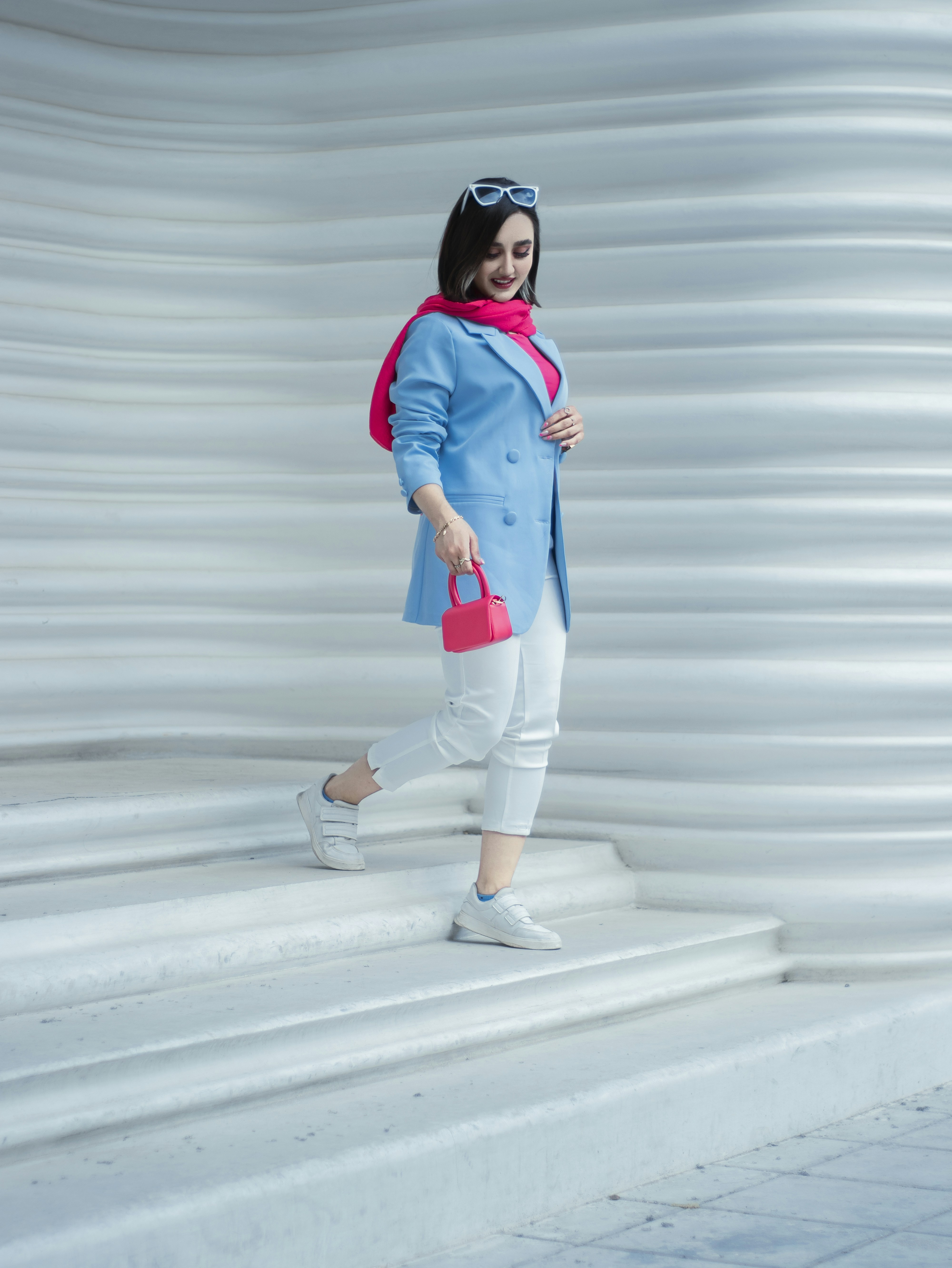 Una donna in un cappotto blu e pantaloni bianchi