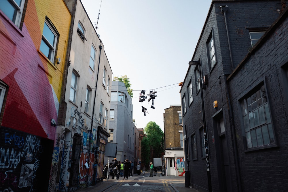 a street with graffiti on the buildings and people walking on the sidewalk