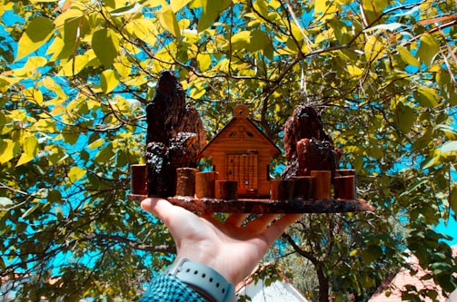 Close-up of hands holding a miniature house model on blueprints.