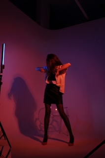 Elara standing confidently in a minimalist studio with futuristic geometric shapes and soft purple lighting.