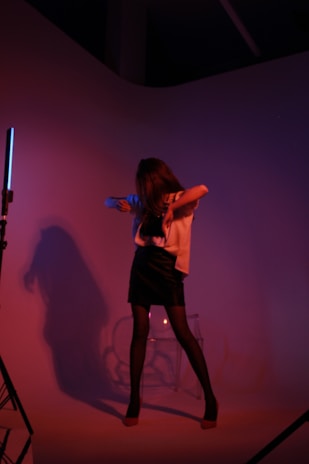 Elara standing confidently in a minimalist studio with futuristic geometric shapes and soft purple lighting.