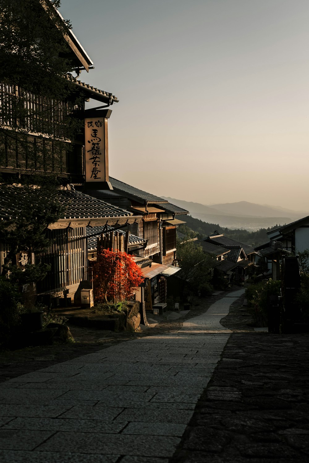 a narrow street with a building and mountains in the background