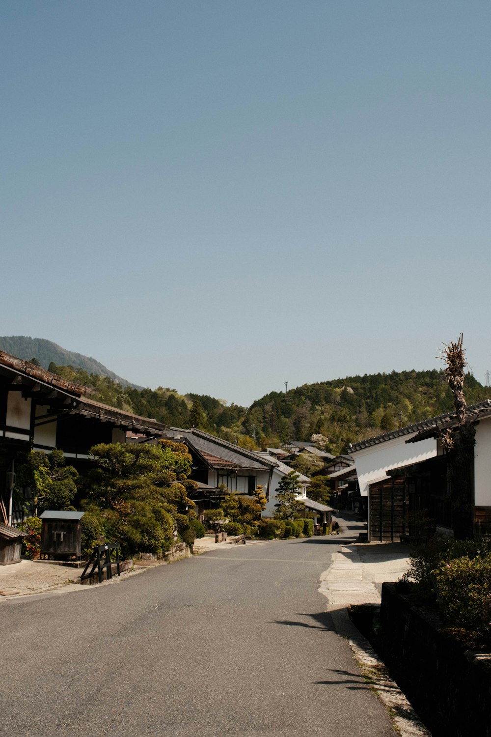 an empty street in a village with mountains in the background