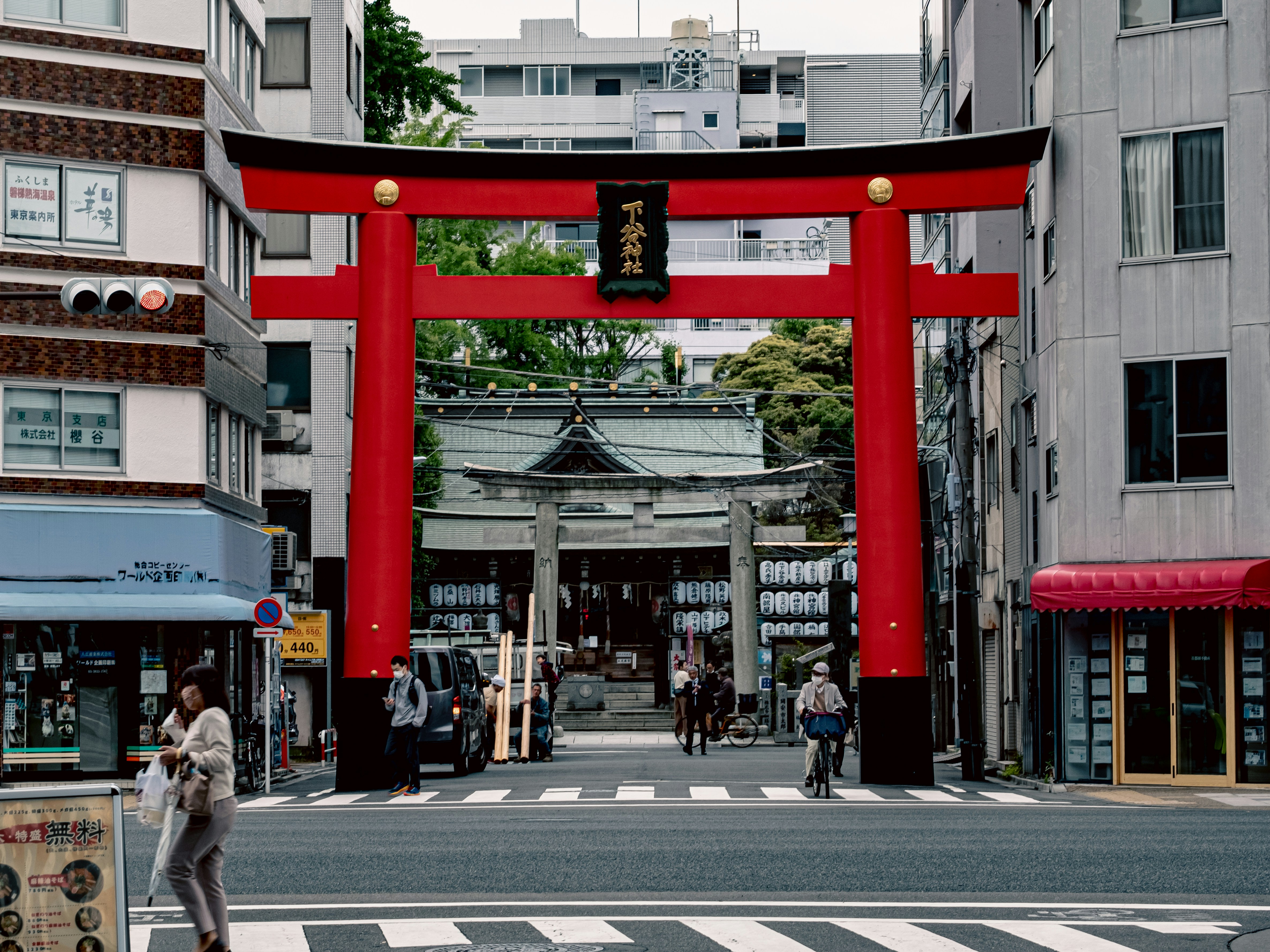 a person crossing a street in front of a red gate