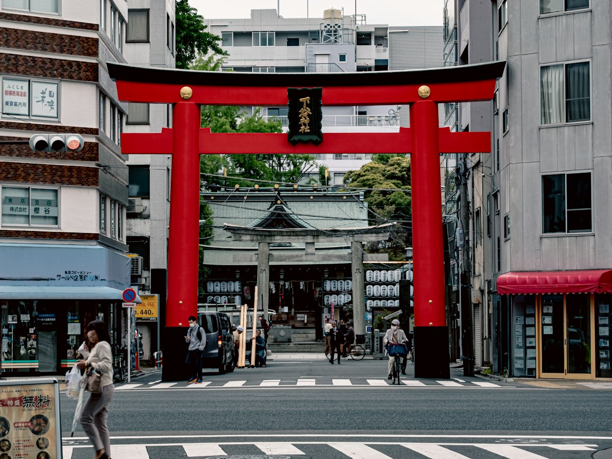 Straßenszene in Tokio mit Torii-Tor, Passanten und Fahrrad