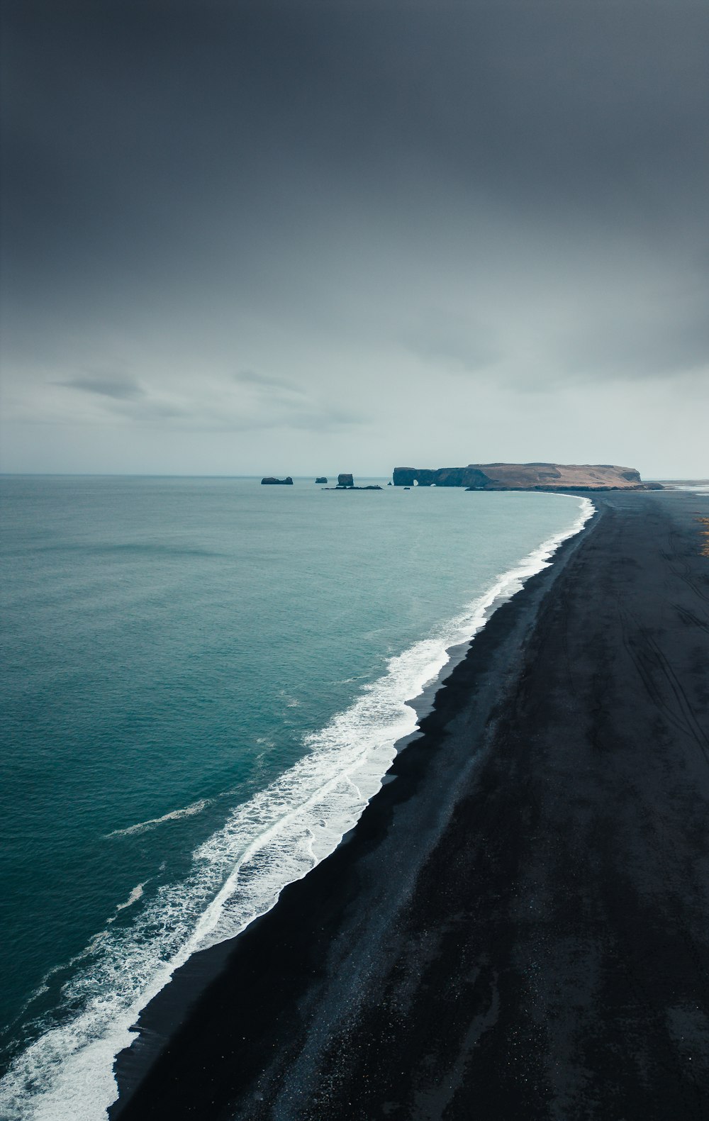 a black sand beach on a cloudy day