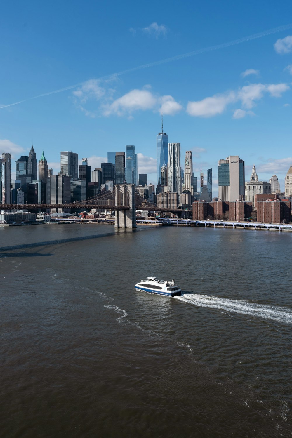 a boat traveling down a river in front of a large city