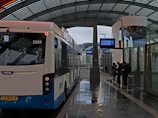 Modern bus stop with digital schedule displays and waiting passengers.