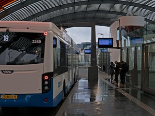 A bus station with people waiting for their rides.