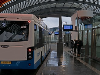 A happy traveler checking their itinerary on a smartphone while waiting at a busy bus station.