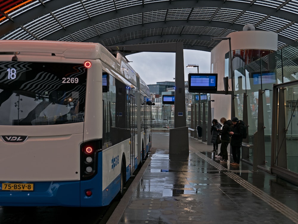 Un autobús blanco y azul estacionado en una parada de autobús