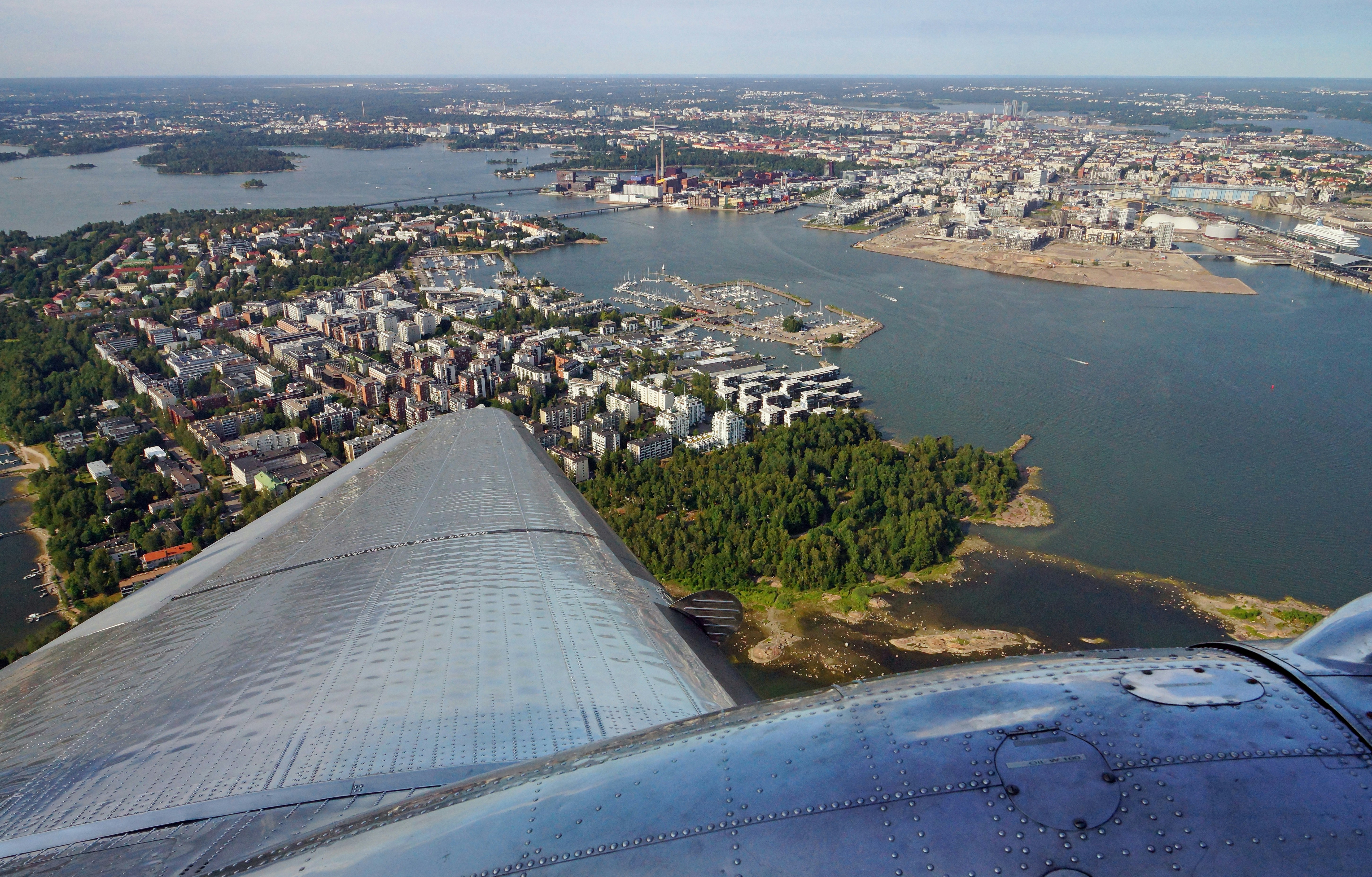 an aerial view of a city and a river, Aerial view of Helsinki, Finland (Lauttasaari on the left) taken from a DC-3 plane, which was built by Douglas Aircraft Company in Santa Monica, California in 1942. The plane flew as softly as a feather!