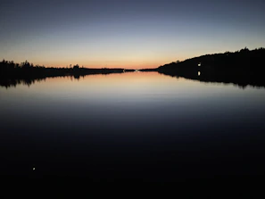A peaceful view of Charco Azul’s deep blue waters reflecting the surrounding forest at sunset.