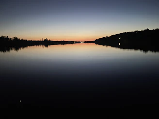 A peaceful view of Charco Azul’s deep blue waters reflecting the surrounding forest at sunset.