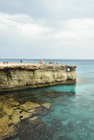 A small group enjoying a peaceful moment atop a Tulum cliff, overlooking the sea and ancient ruins.