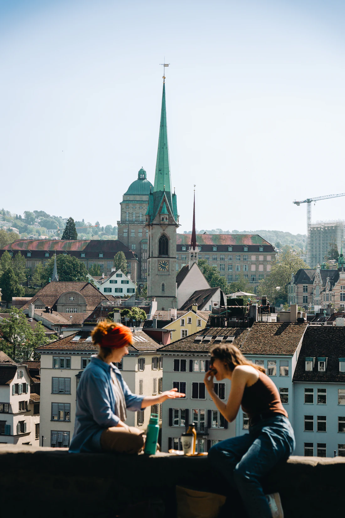 Two friends sitting on a rooftop above Zürich's old town in the evening sun