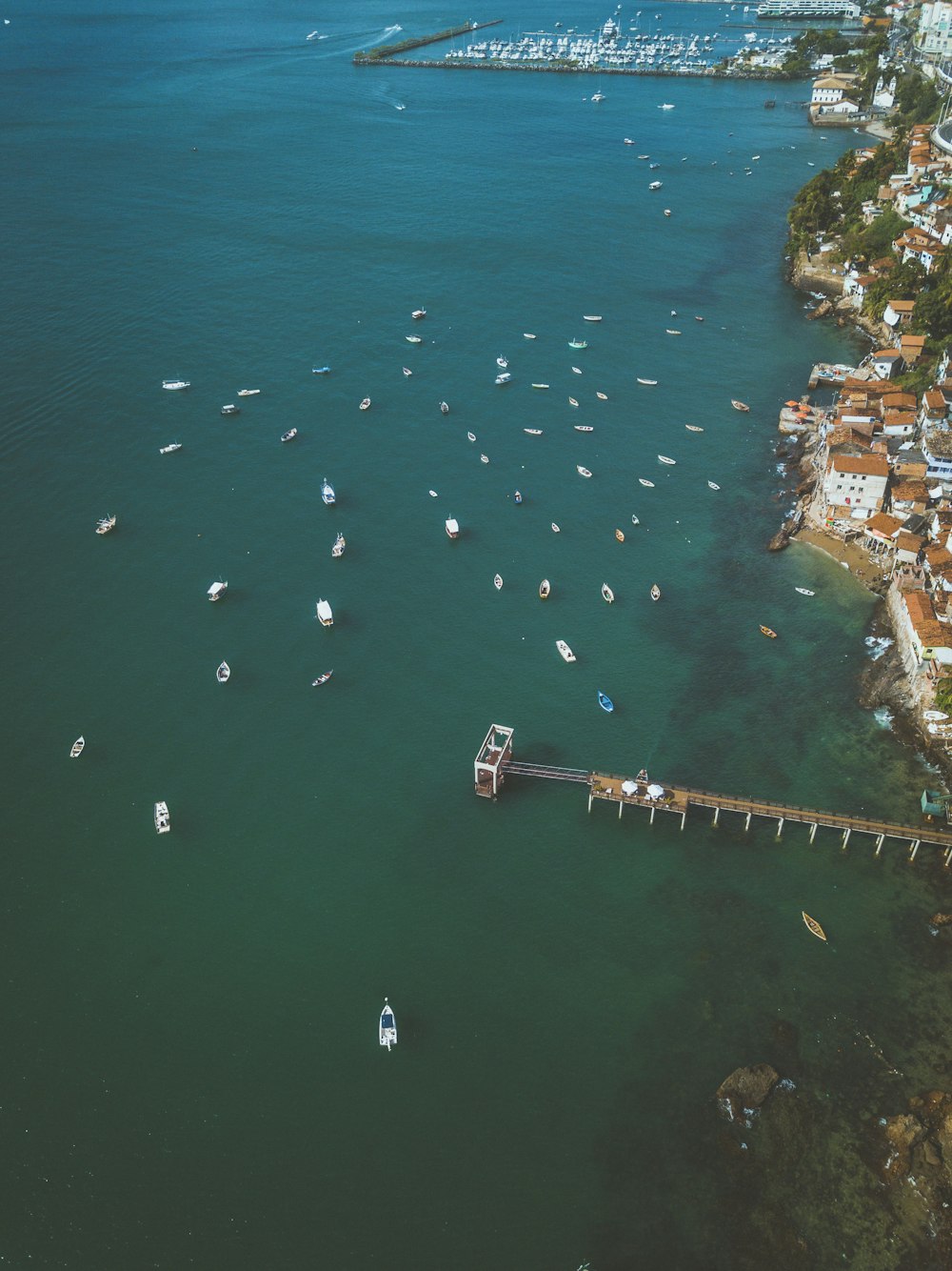 an aerial view of boats in the water near a pier