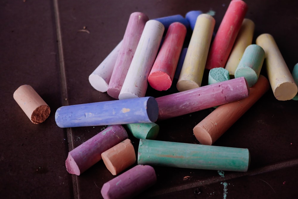 a pile of colored crayons sitting on top of a floor