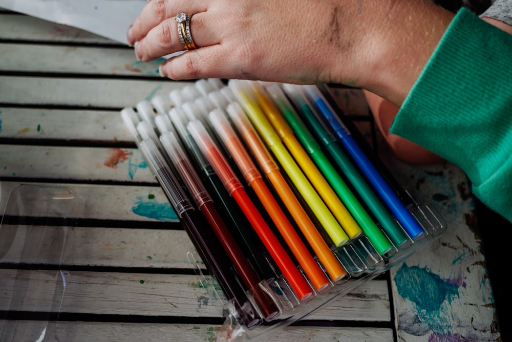 a person holding a box of colored pens