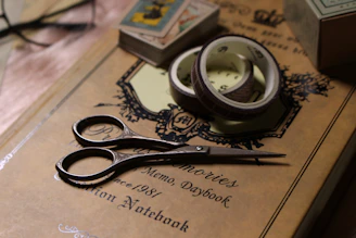 Compact travel scissors with protective case placed beside a notebook and pen.